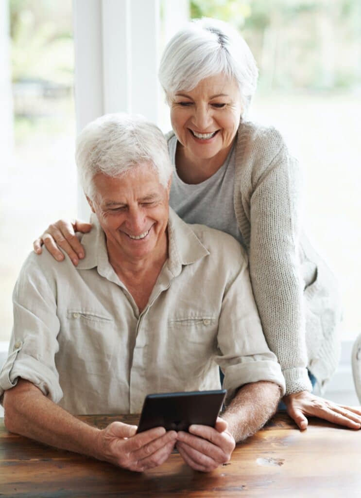A senior couple examining a digital tablet as they sit at they dining room table